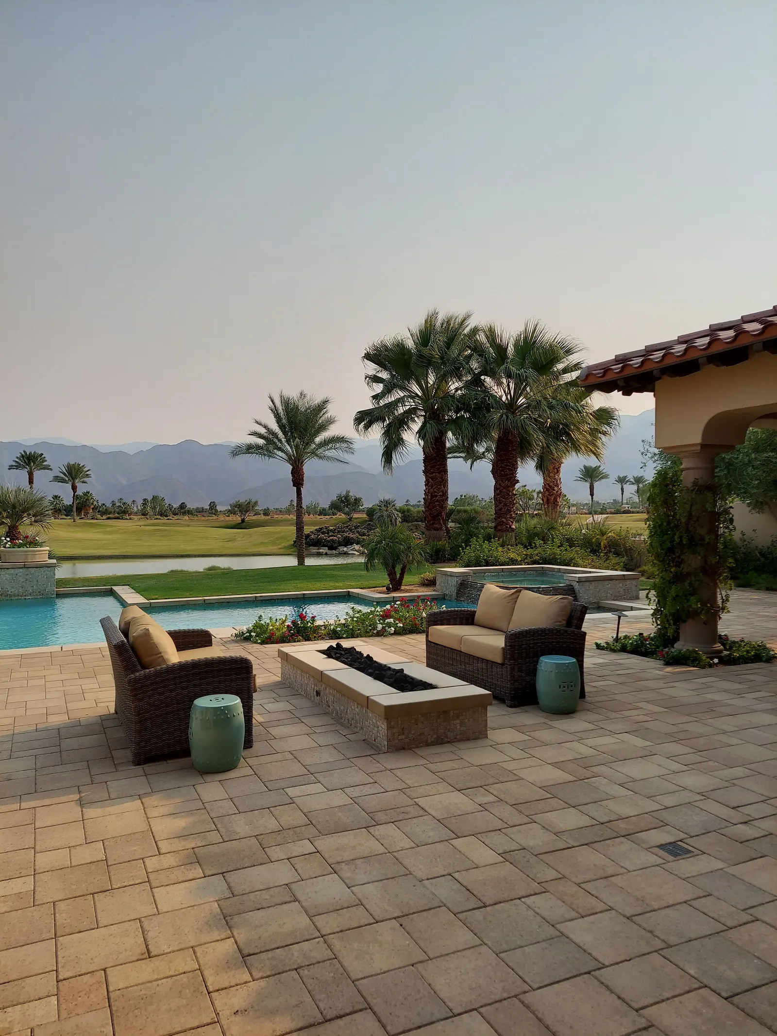 Backyard paver patio with a central fire pit and surrounding seating area